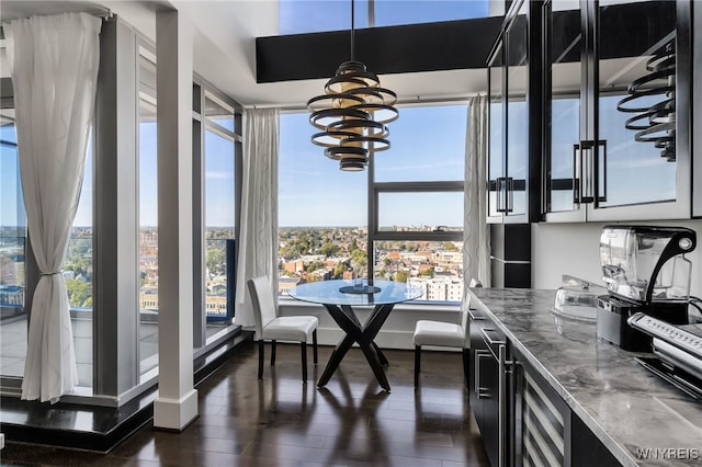 interior space featuring decorative light fixtures, an inviting chandelier, dark cabinetry, and dark wood finished floors