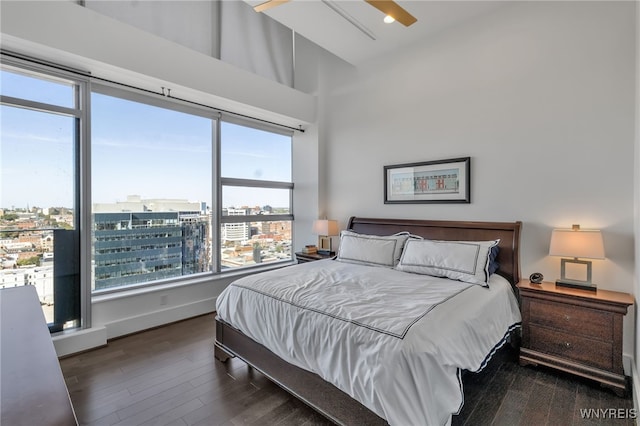 bedroom featuring a city view, a towering ceiling, and wood finished floors