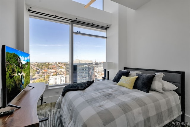 bedroom with baseboards, multiple windows, and a city view