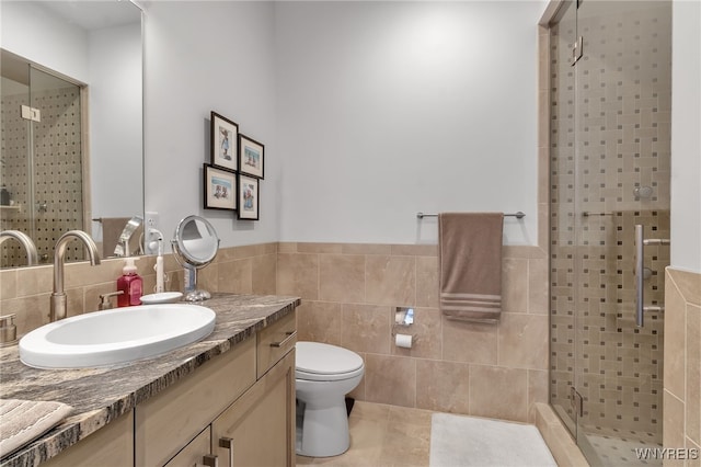 full bathroom featuring vanity, a stall shower, tile patterned floors, toilet, and tile walls