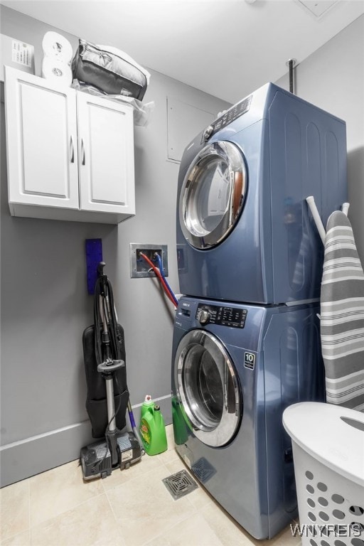 clothes washing area featuring tile patterned floors, stacked washer / dryer, baseboards, and visible vents
