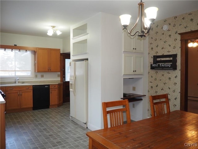 kitchen with wallpapered walls, light countertops, white refrigerator with ice dispenser, dishwasher, and a notable chandelier