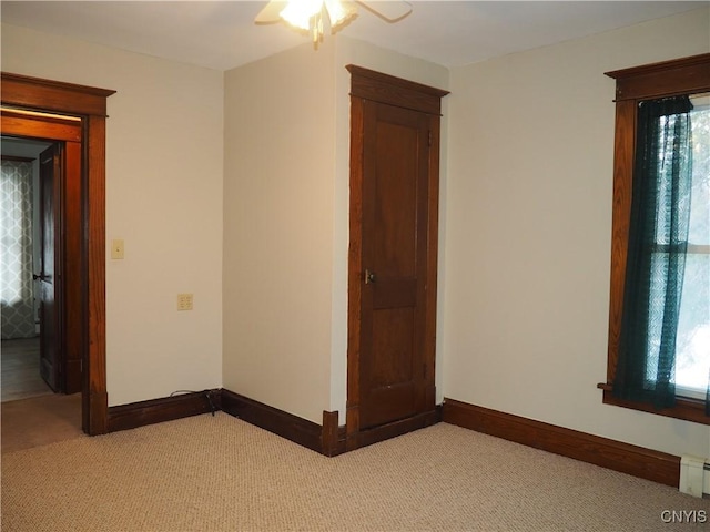 unfurnished room featuring a ceiling fan, baseboards, and light carpet