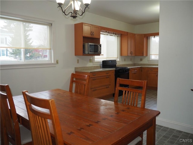 kitchen featuring black gas range, stainless steel microwave, a wealth of natural light, and a chandelier