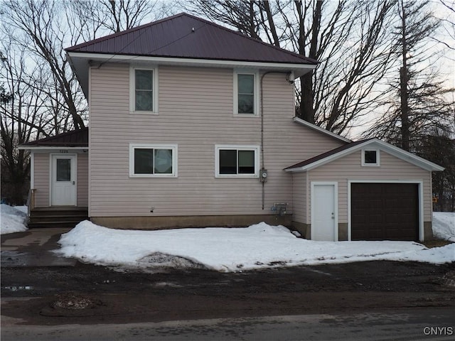 exterior space with entry steps, a garage, and metal roof