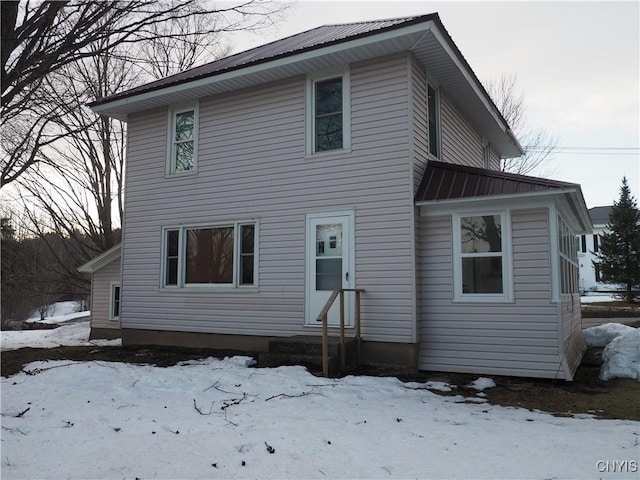 snow covered rear of property with entry steps and metal roof