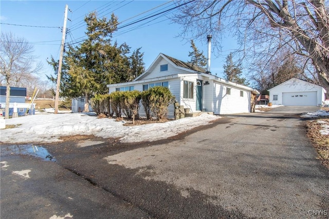 view of front of property featuring entry steps, an outdoor structure, driveway, and a garage