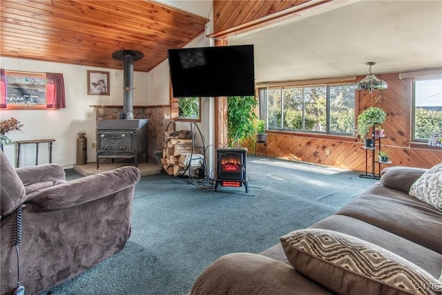 carpeted living room with wooden ceiling, wood walls, and a wood stove