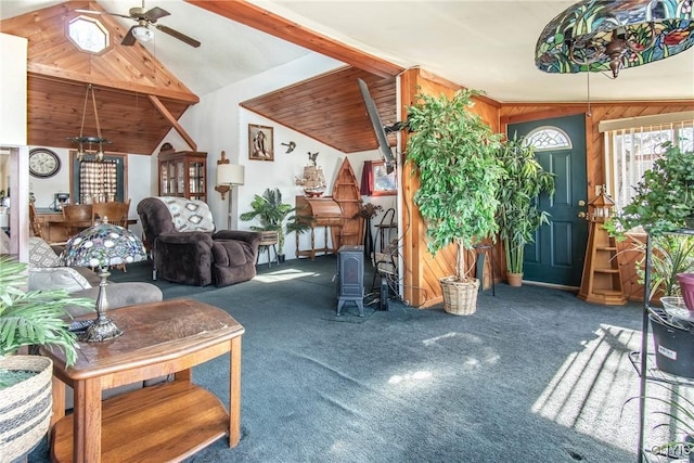 living area with a ceiling fan, wood walls, carpet floors, and high vaulted ceiling