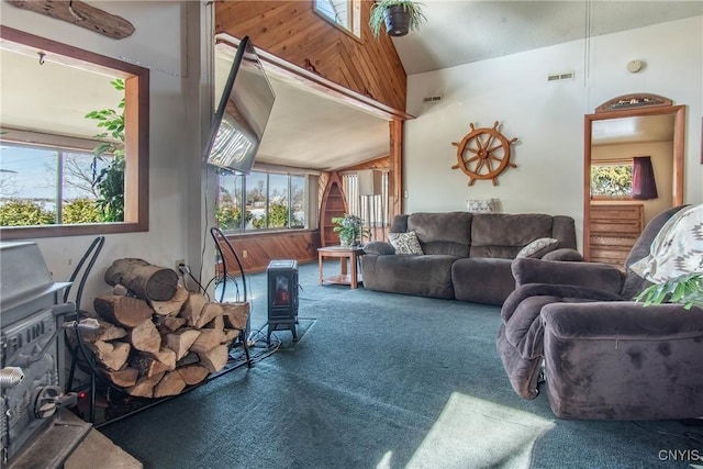 living room featuring a wealth of natural light, visible vents, a wood stove, and carpet