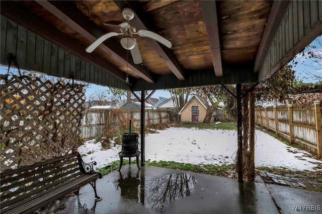 snow covered patio with a ceiling fan and a fenced backyard