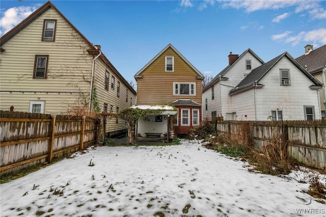 snow covered back of property with a fenced backyard