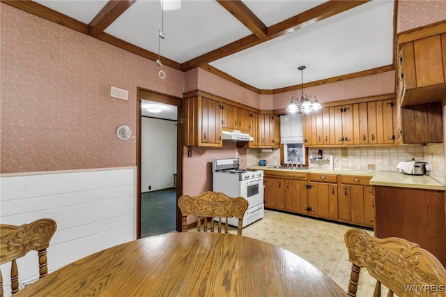 kitchen featuring white gas stove, under cabinet range hood, wainscoting, wallpapered walls, and light floors