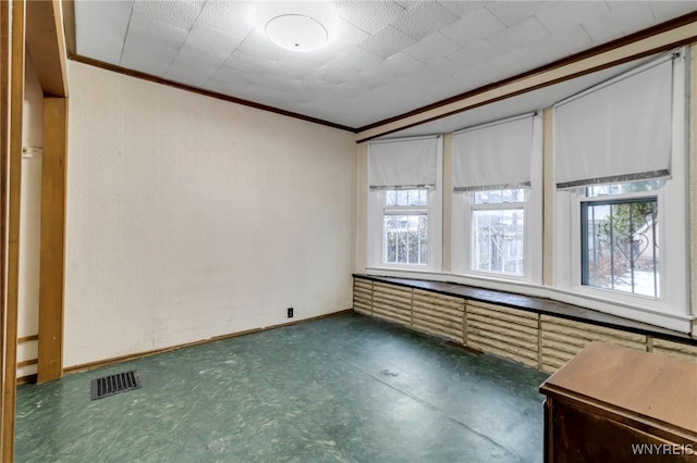 unfurnished room featuring baseboards, visible vents, and ornamental molding