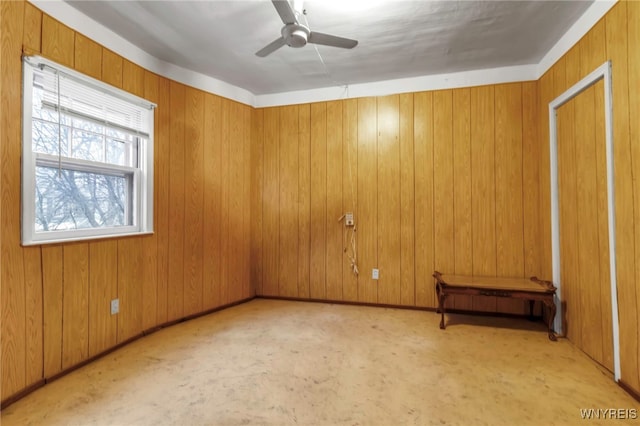 unfurnished room with wood walls and a ceiling fan