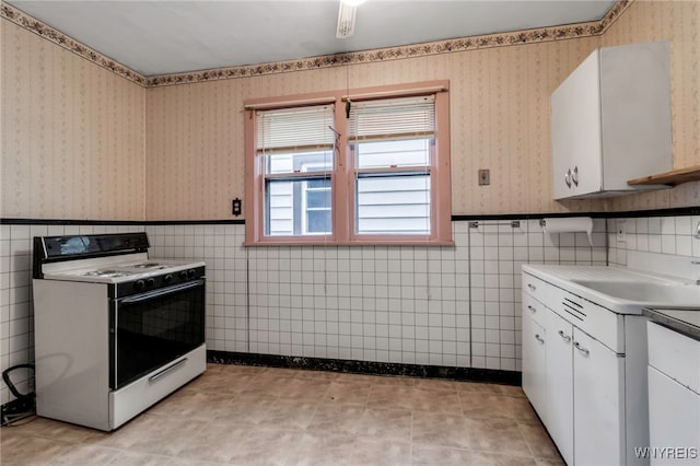 kitchen featuring wainscoting, white cabinets, wallpapered walls, and white electric range oven