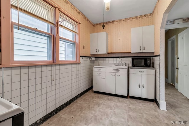 kitchen with white cabinets, wallpapered walls, light countertops, and black microwave