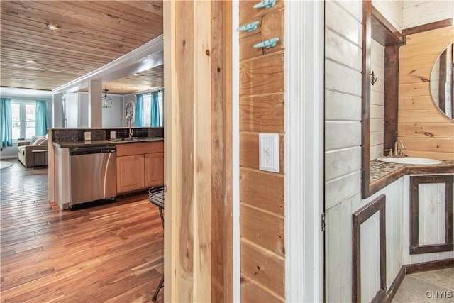 kitchen featuring stainless steel dishwasher, dark countertops, open floor plan, and a sink