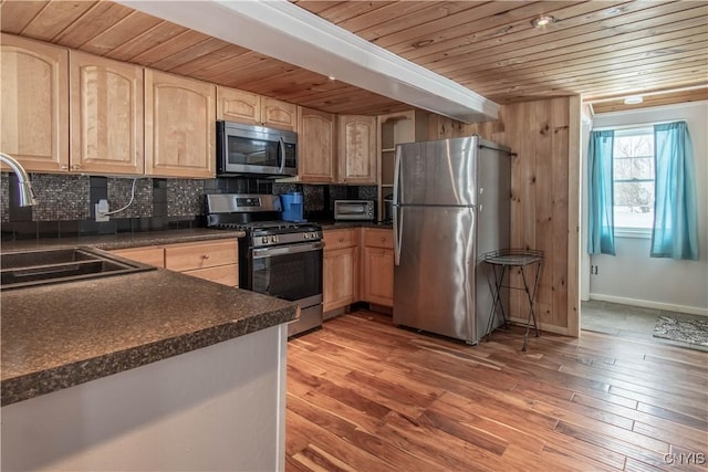 kitchen featuring dark countertops, backsplash, appliances with stainless steel finishes, and light brown cabinets