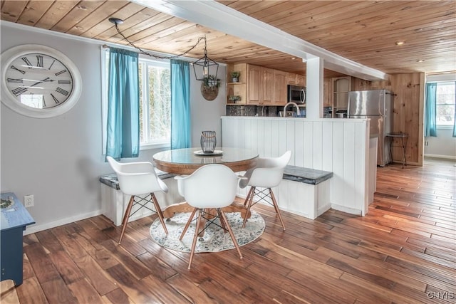 dining room featuring baseboards, wood finished floors, beamed ceiling, and wooden ceiling