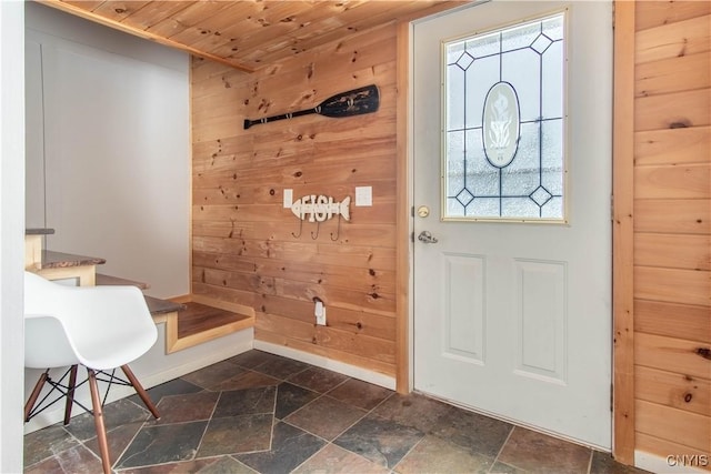 entrance foyer featuring stone tile floors, wooden walls, wooden ceiling, and baseboards