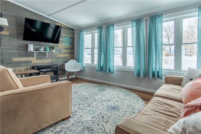 living area with an accent wall, baseboards, vaulted ceiling, a fireplace, and wood finished floors