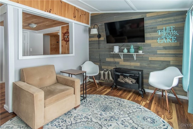 sitting room with lofted ceiling, wooden walls, wood finished floors, and a wood stove