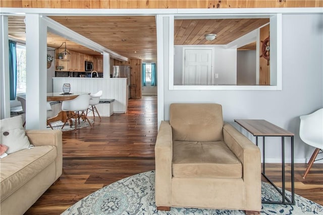 living room featuring baseboards, wood finished floors, and wooden ceiling