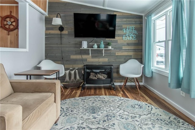 living area featuring an accent wall, baseboards, wood walls, lofted ceiling, and wood finished floors