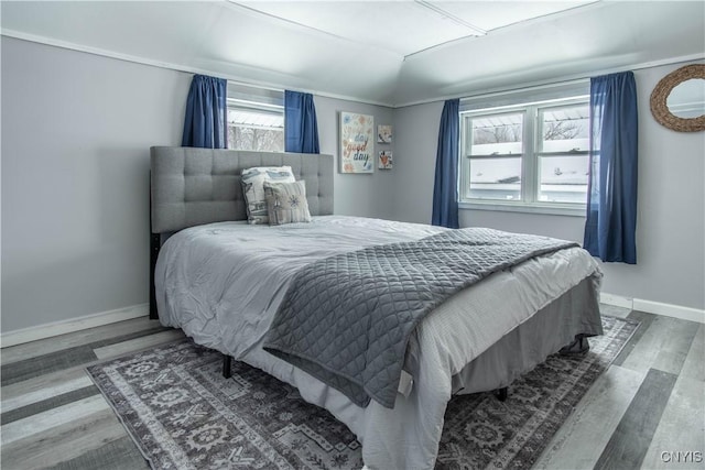 bedroom featuring lofted ceiling, baseboards, and wood finished floors