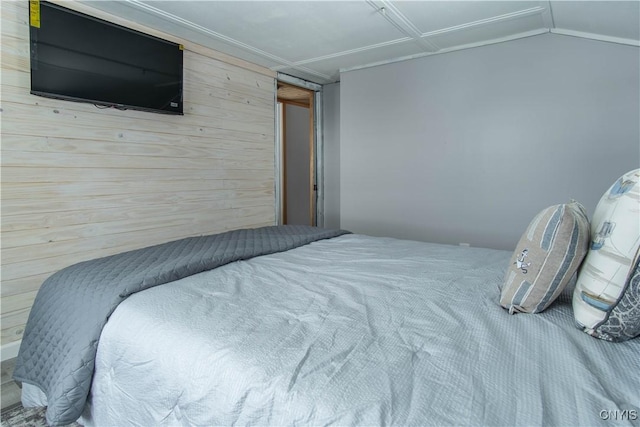 bedroom featuring wooden walls and vaulted ceiling