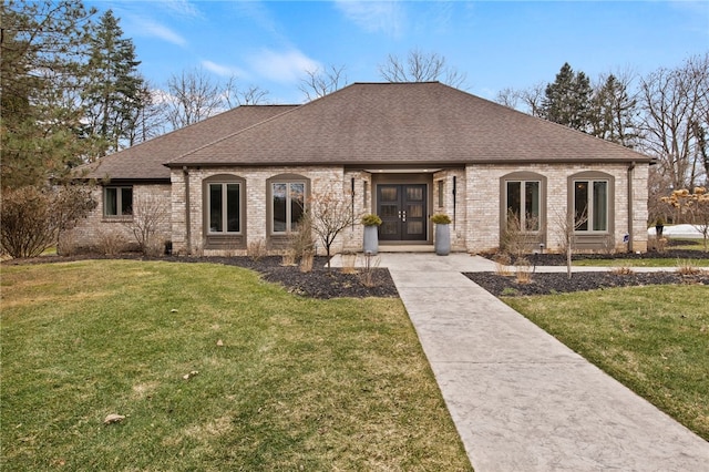 french country style house featuring a front yard, brick siding, driveway, and a shingled roof