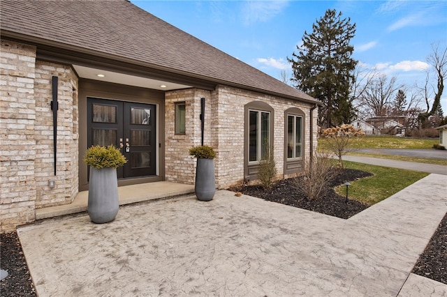 property entrance featuring brick siding and roof with shingles