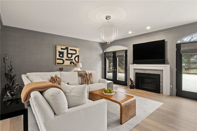 living area featuring a glass covered fireplace, recessed lighting, wood finished floors, and ornamental molding