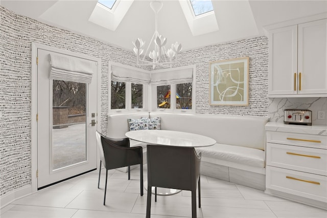 dining area with light tile patterned floors, lofted ceiling with skylight, and an inviting chandelier