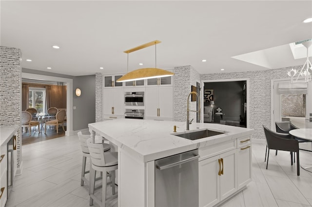 kitchen with white cabinets, a skylight, appliances with stainless steel finishes, and a sink