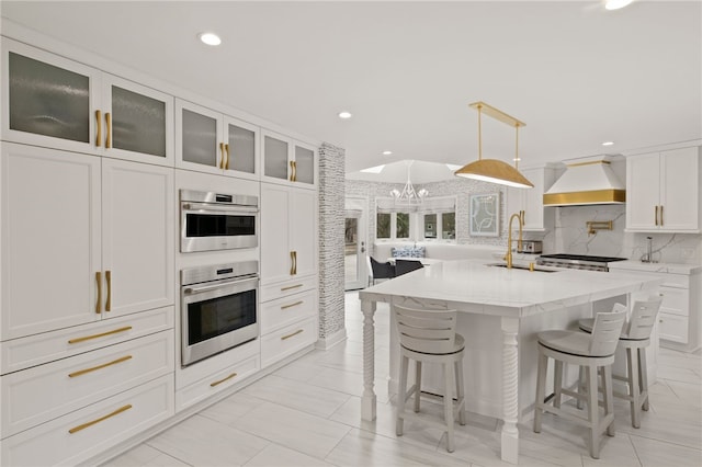 kitchen with oven, a breakfast bar, white cabinets, and custom range hood