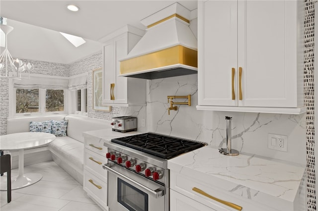 kitchen with premium range hood, a skylight, high end range, and white cabinets