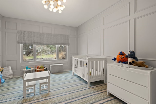 bedroom featuring a chandelier, a decorative wall, light carpet, and a nursery area