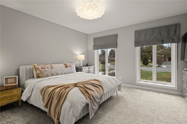 carpeted bedroom with a notable chandelier, visible vents, and baseboards