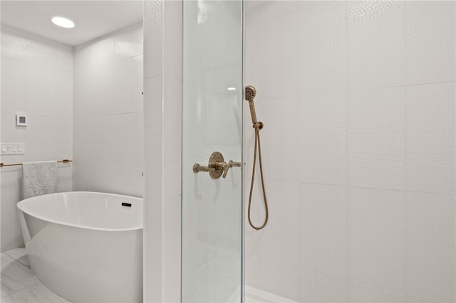 full bath featuring a freestanding tub and a tile shower