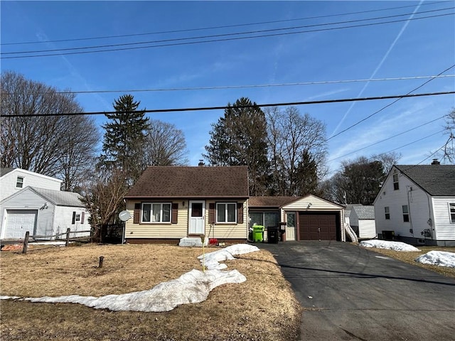 view of front facade featuring fence, driveway, roof with shingles, an outdoor structure, and a detached garage