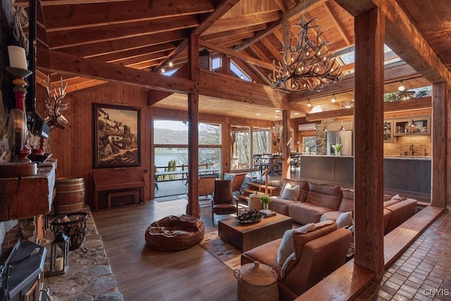 living room with wood finished floors, high vaulted ceiling, wood walls, beamed ceiling, and a notable chandelier