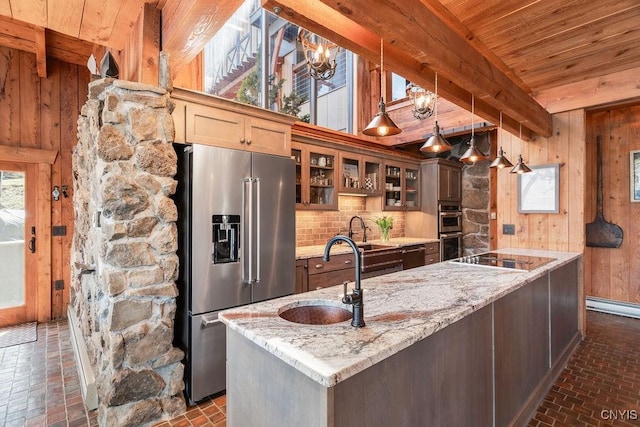 kitchen with wood walls, appliances with stainless steel finishes, wooden ceiling, brick floor, and a sink