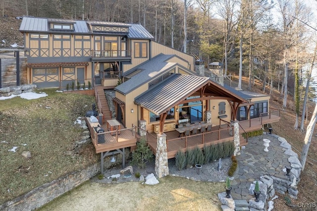 rear view of property with a deck, metal roof, stairs, and a standing seam roof