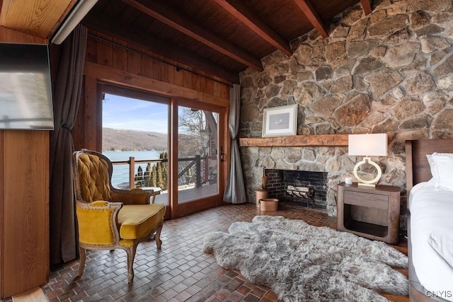 living area with a stone fireplace, wood ceiling, lofted ceiling with beams, and brick floor