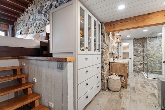 bathroom with beam ceiling, wood finished floors, wood ceiling, and a stall shower