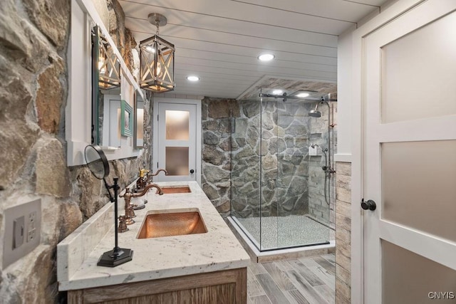 bathroom featuring double vanity, a marble finish shower, and a sink