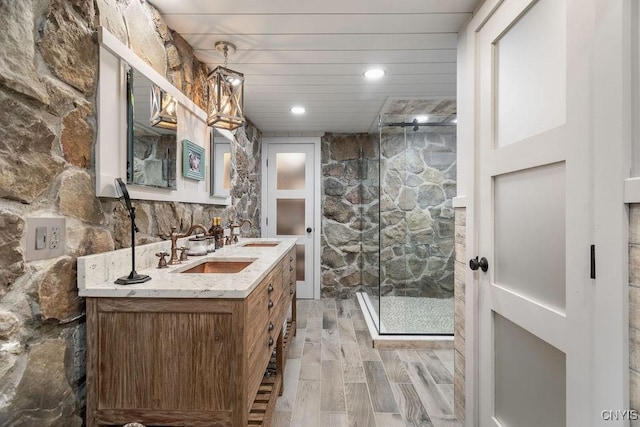 bathroom featuring double vanity, a stall shower, and a sink