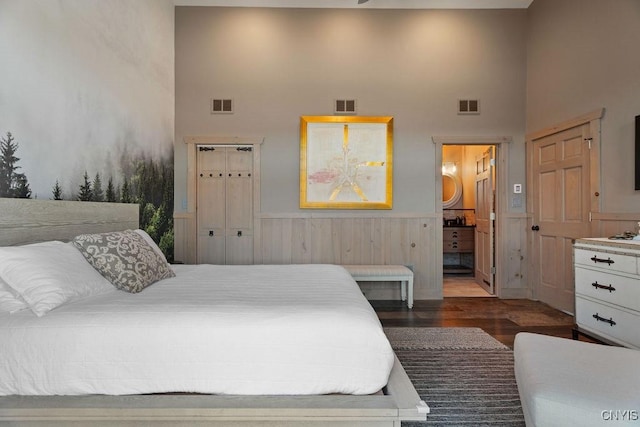 bedroom with wood finished floors, visible vents, and wainscoting